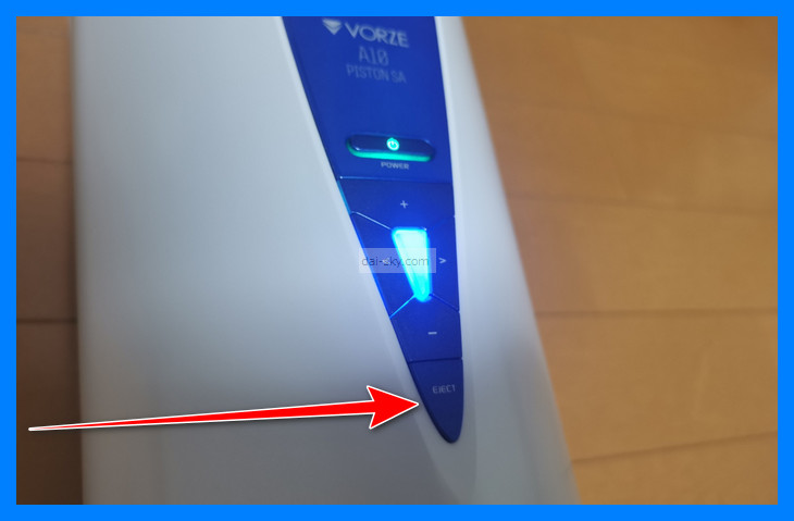 Arrow pointing to the eject button at the bottom of the control panel